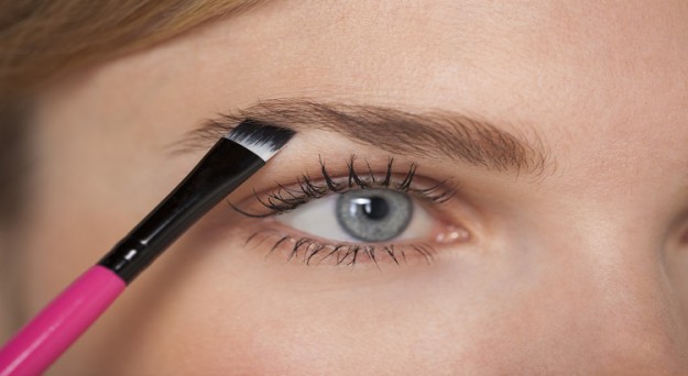 Beautiful woman brushing eyebrow