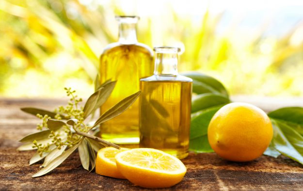 Massage oil bottles with lemons and green leaves at spa outdoors. Front view, Horizontal shot.