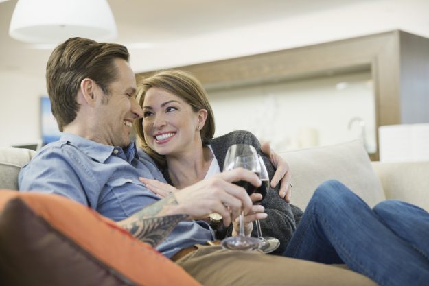 Couple drinking wine on living room sofa