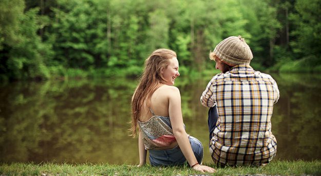 Rear view of couple sitting near lake