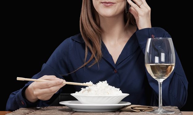 Woman talking on a mobile phone and eating rice